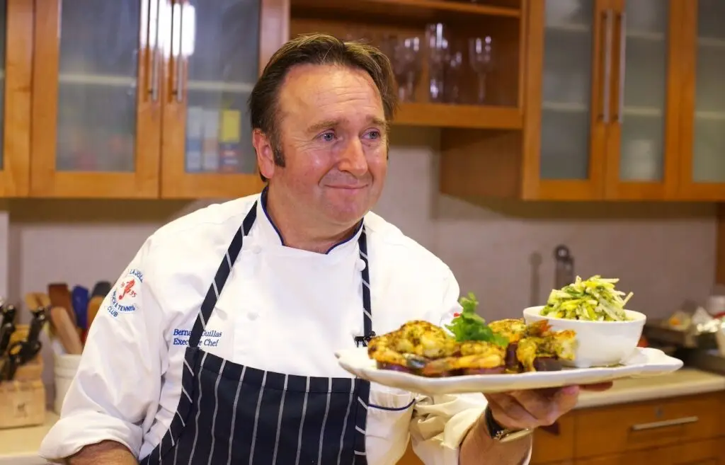 Chef Bernard holding a plate of grilled shrimp.