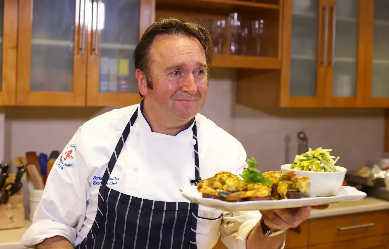 Chef Bernard holding a plate of grilled shrimp.