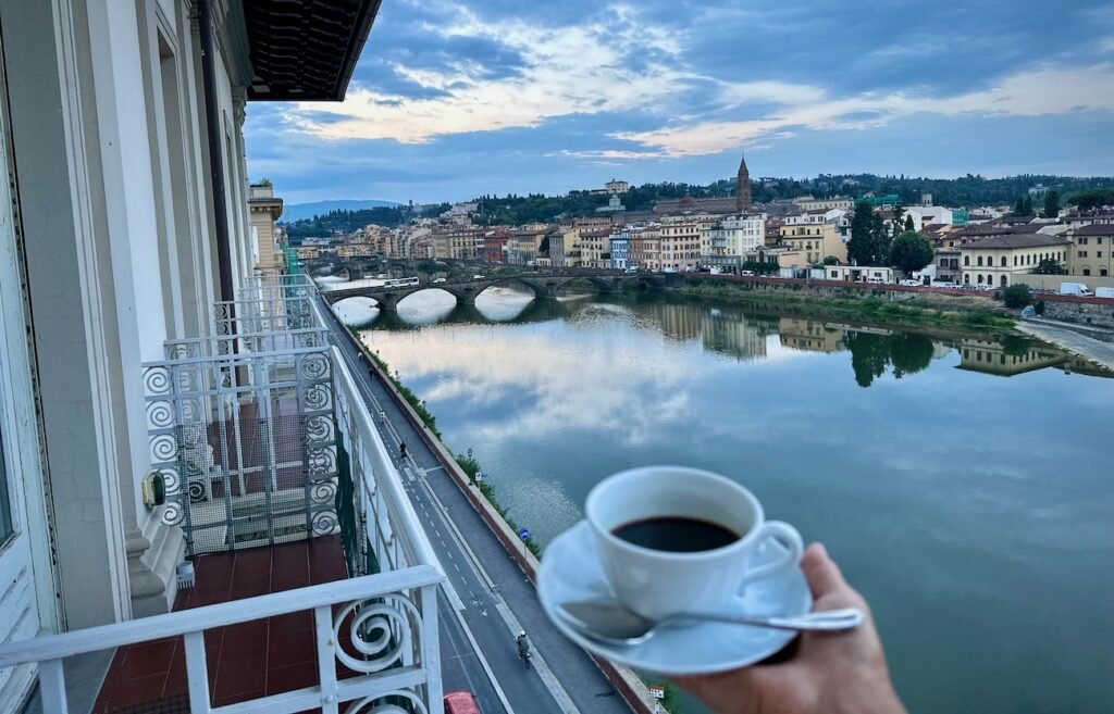 Holding coffee with a view of the Arno in Florence, Italy in the background