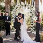 Outdoor wedding ceremony in the Rose Garden at Rancho Valencia surrounded by blooming flowers and Spanish-style architecture