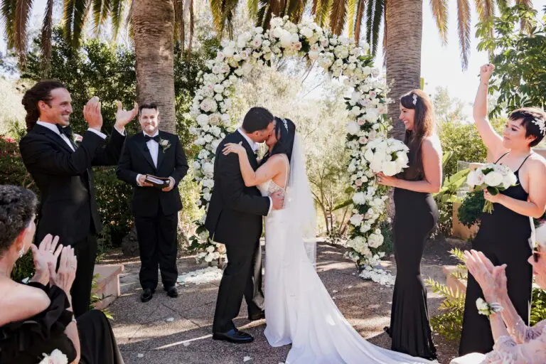 Outdoor wedding ceremony in the Rose Garden at Rancho Valencia surrounded by blooming flowers and Spanish-style architecture