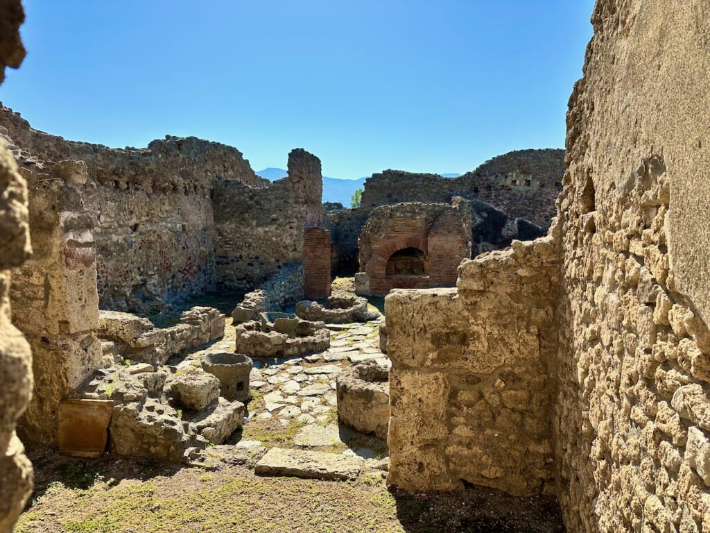 Pompeii's ancient ruins show detailed stonework and a brick hearth space.