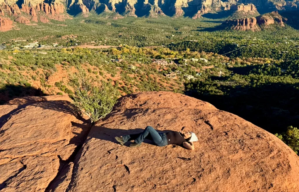 Phoebe relaxing on a red rock overlook with panoramic Sedona canyon and mesa views.