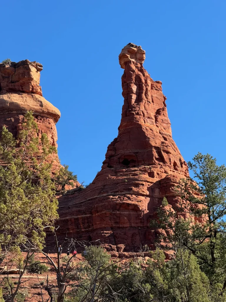 Tall red rock spire rising above the Boynton Canyon landscape under a clear sky.
