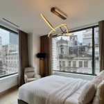 Luxury hotel bedroom with floor-to-ceiling windows overlooking historic New York City buildings at The Ritz-Carlton NoMad