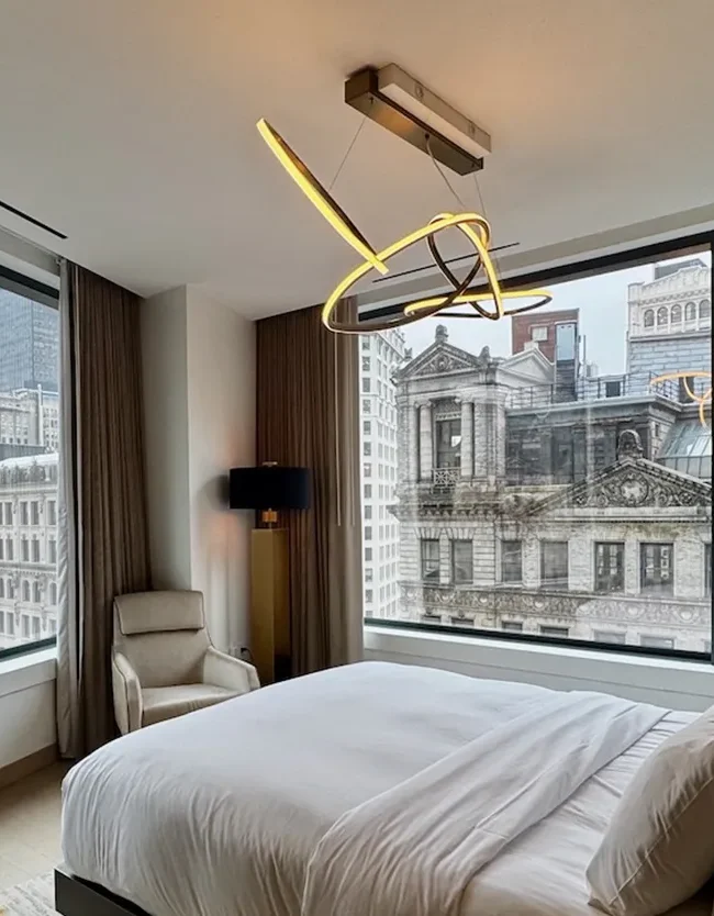 Luxury hotel bedroom with floor-to-ceiling windows overlooking historic New York City buildings at The Ritz-Carlton NoMad