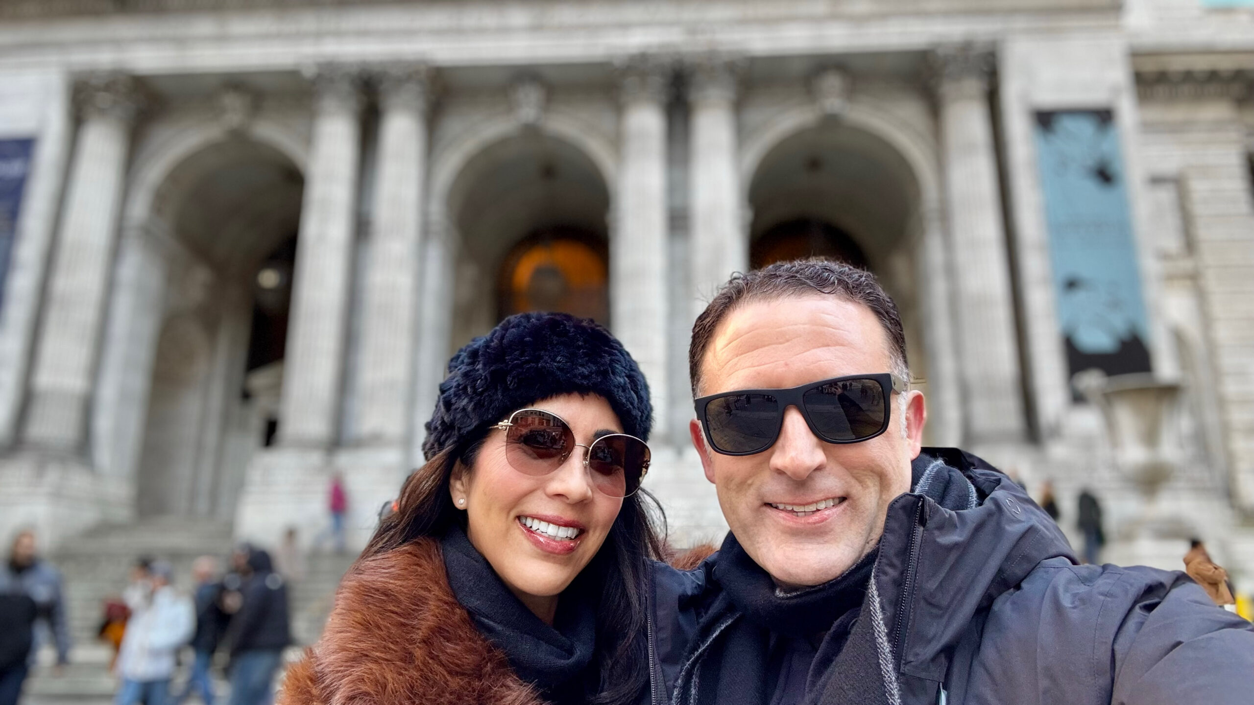 Phoebe Chongchua and John Pollard smiling in front of historic architecture in New York City